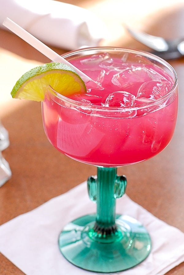 Prickly Pear Margarita in cactus glass with straw and lime wedge