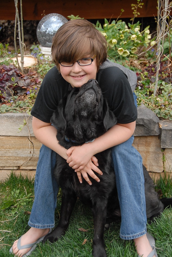 A little boy that is standing in the grass with dog