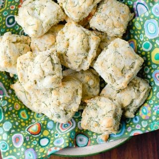 Tangy, homey gluten-free goat cheese dill mini biscuits on a green napkin in a white bowl on dark wood BoulderLocavore.com