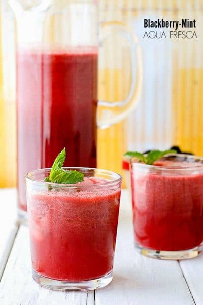 Fresh, light Blackberry Mint Agua Fresca with fresh mint sprigs on vintage white wood with yellow background
