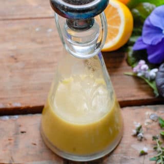 Homemade Meyer Lemon Salad Dressing in a cut crystal vintage carafe with fresh greens