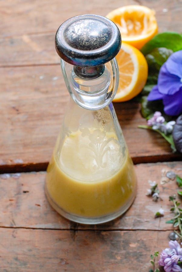 Cut glass carafe of Homemade Meyer Lemon Salad Dressing on a wooden surface