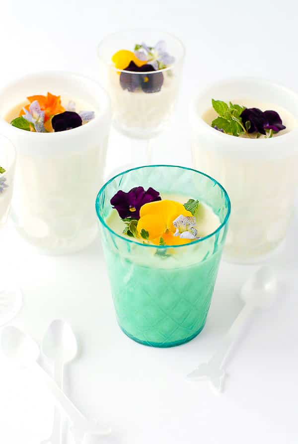 Rose-flavored Panna Cotta with edible flowers in decorative cups 