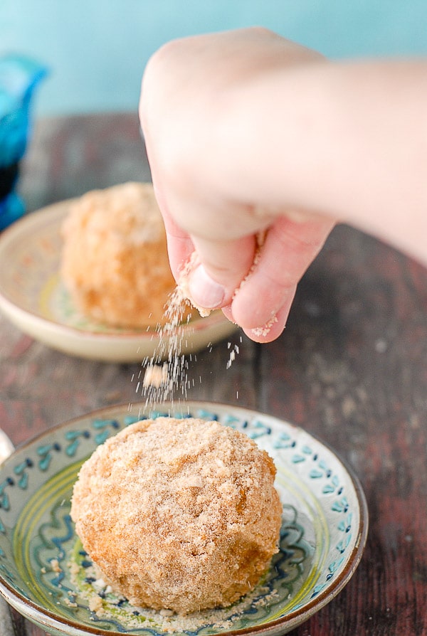 sprinkling cinnamon sugar on fried ice cream balls