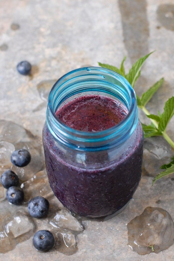 Fresh and icy Blueberry Mint Daiquiri in a blue glass jar with sprig of fresh mint 