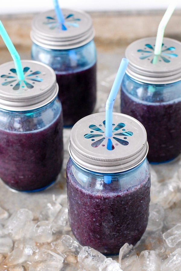 Fresh, frozen Blueberry Mint Daiquiri cocktails in blue pint Mason jars with metal flower lids 