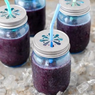 Fresh, frozen Blueberry Mint Daiquiris in blue Mason jars with flower lids