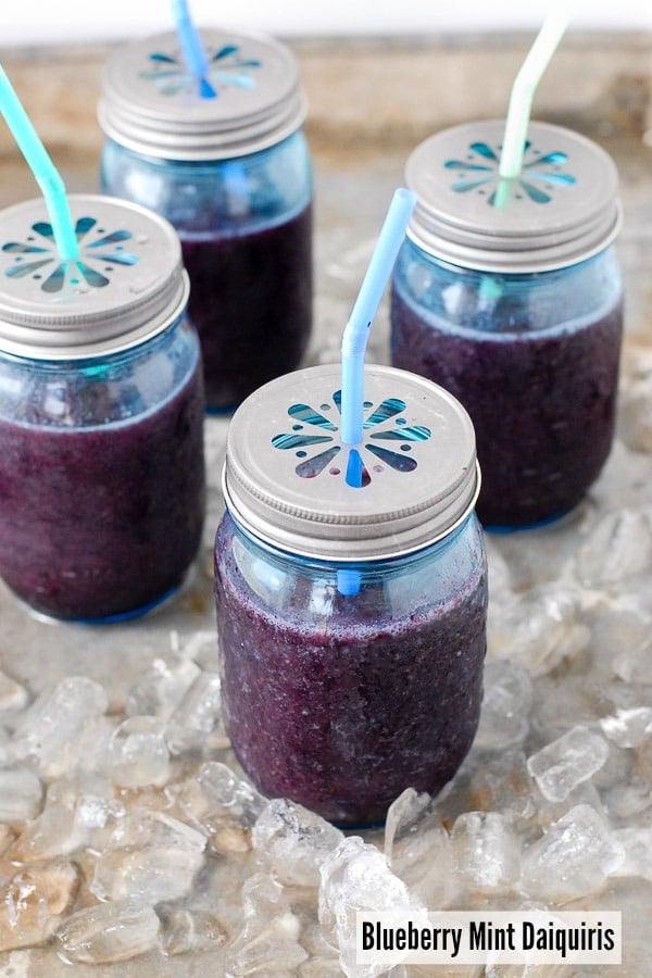 Fresh, frozen Blueberry Mint Daiquiris in blue Mason jars with flower lids 