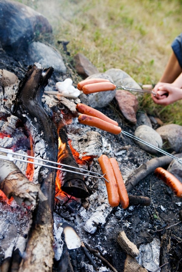 Roasting hot dogs over an open campfire