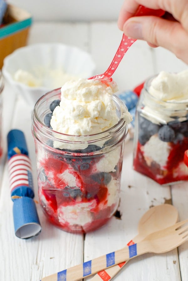 Adding whipping cream to 4th of July desserts with red polka dot spoon