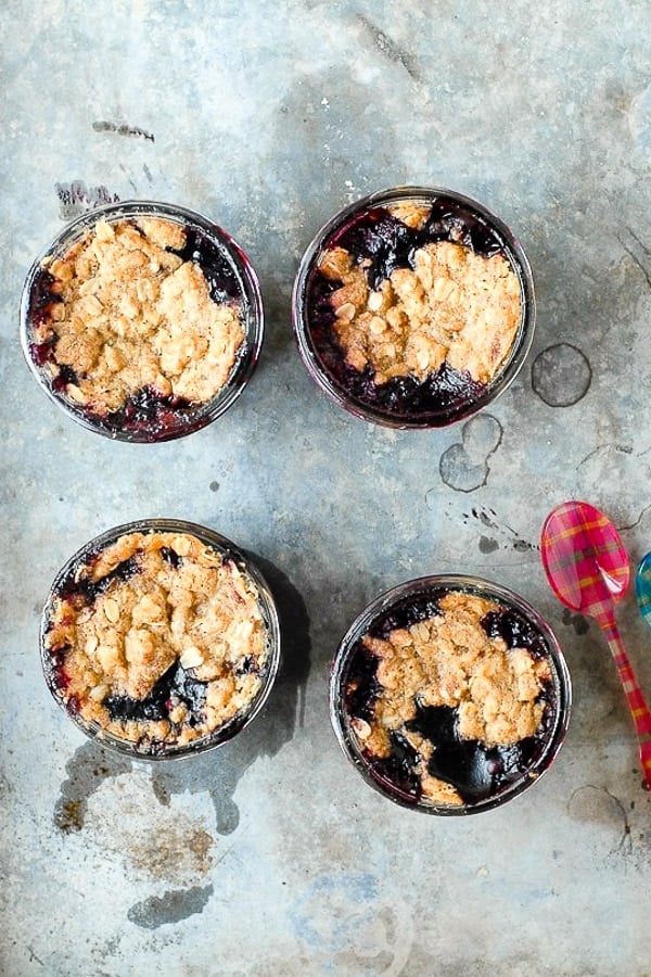 Fresh from the oven Blueberry Mint Crumble desserts in small jars on a distressed metal surfac