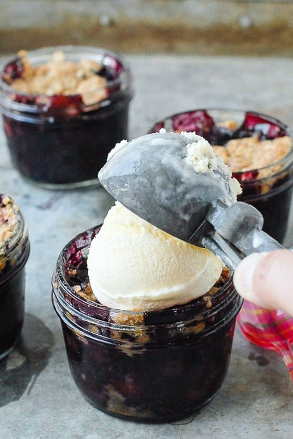 Simple Blueberry Mint Crumble baked in small jars with vanilla ice cream on top 