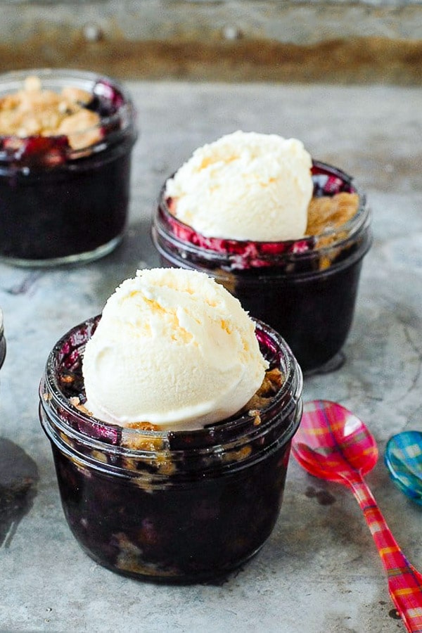 Freshly baked Blueberry Mint Crumble in jars with vanilla ice cream and colorful Sabre spoon 