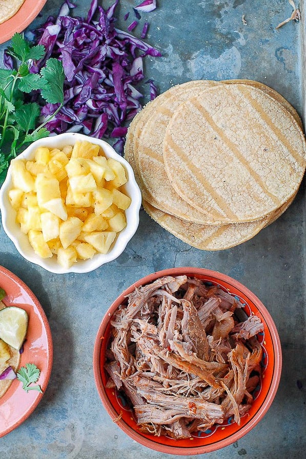 Tacos Al Pastor ingredients: slow cooker pork, pineapple chunks, corn tortillas and red cabbage