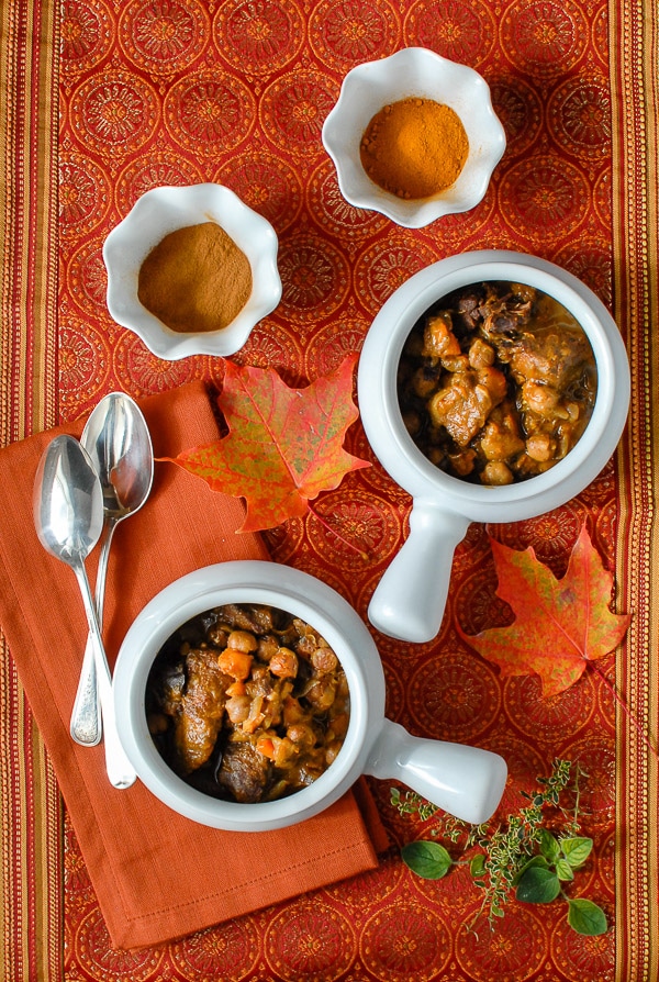 white bowls of Sweet & Spicy Slow Cooker Beef Stew iwth spices and fall leaves