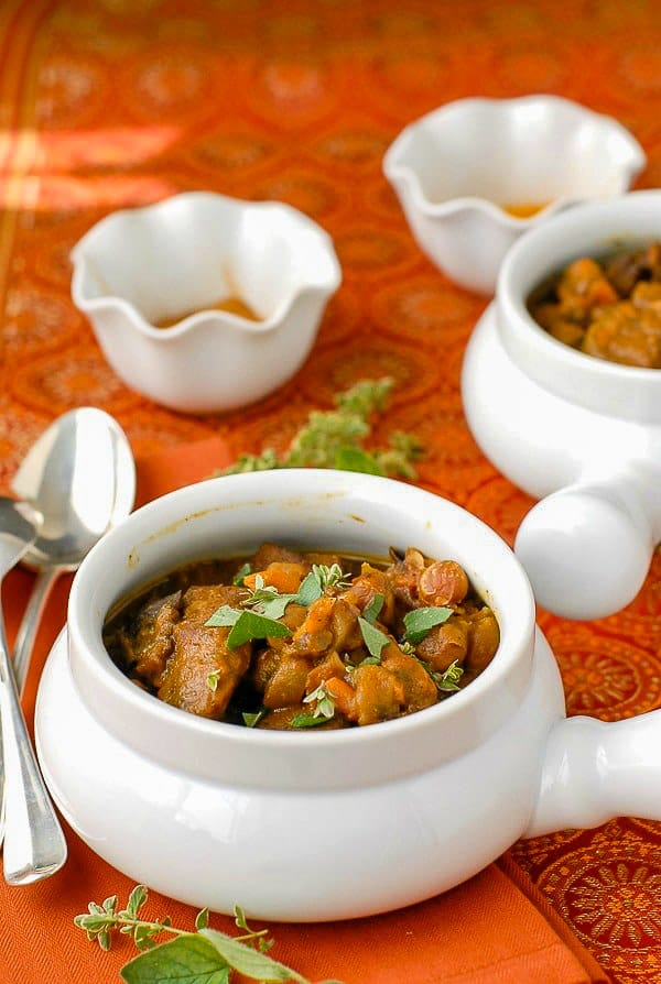 bowl of slow cooker beef stew with fresh herbs and spice bowls