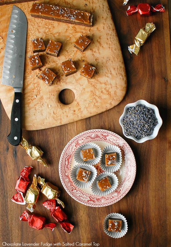 Chocolate Lavender Fudge with Salted Caramel Top cut into small squares on a maple wood cutting board.