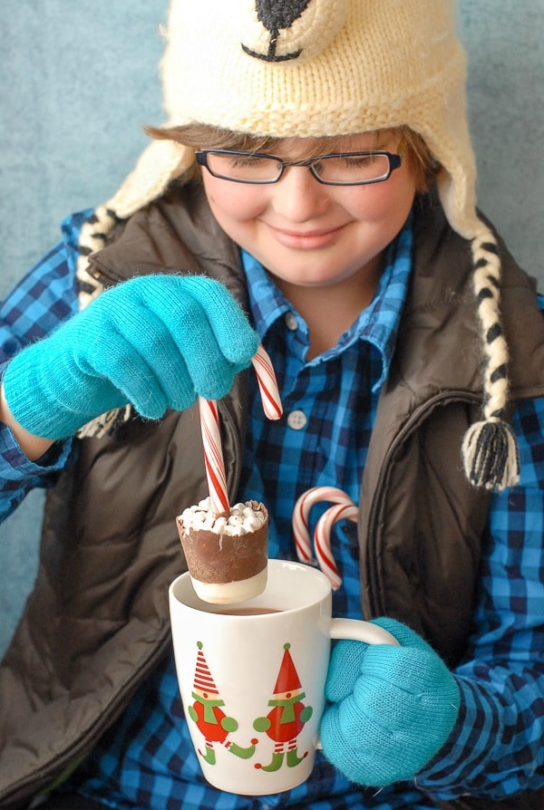 A person holding a cup of hot cocoa and Hot Cocoa Pop hot chocolate