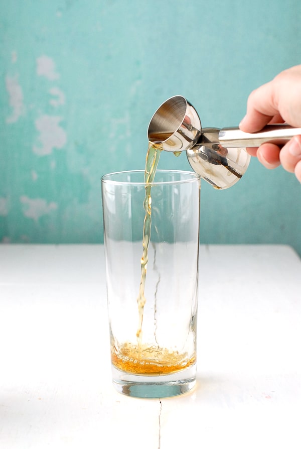 pouring bourbon in a Collins glass