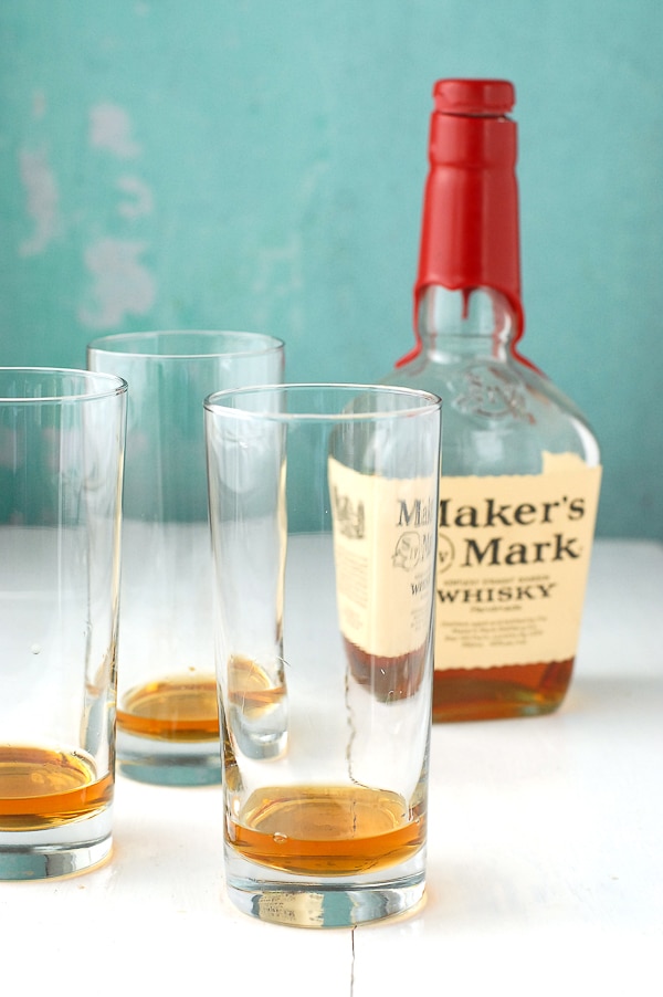 three Collins glasses with bourbon in them and Marker\'s Mark bottle