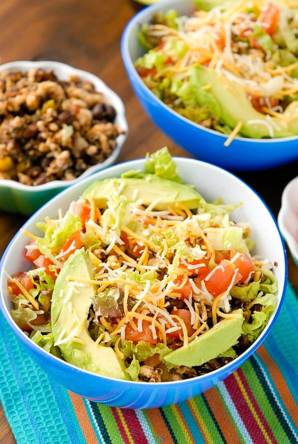 Turkey Black Bean Quinoa Burrito Bowls with shredded lettuce, grated cheese, avocado slices 