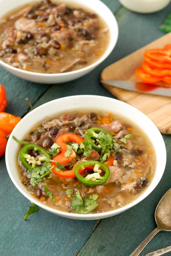 Hot bowl of slow cooker black bean and hambone soup with cumin topped with sliced jalapeno