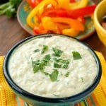 Slow Cooker White Queso Green Chile Dip in blue glass bowl with sliced colorful sweet peppers