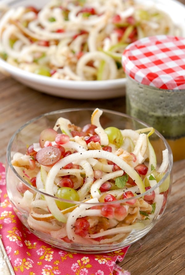 Glass bowl of Spiralized Apple and Pears Pomegranate Slaw with Honey-Poppy Seed Dressing