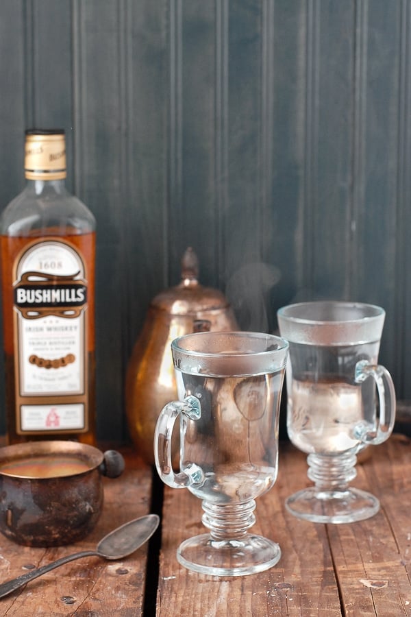 Heating glass mugs with boiling water to prepare for an authentic Irish coffee recipe