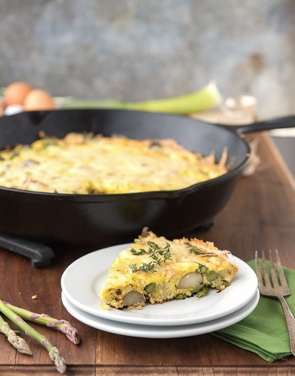 Easy Asparagus Leek New Potato Frittata slice topped with thyme on a white plate 