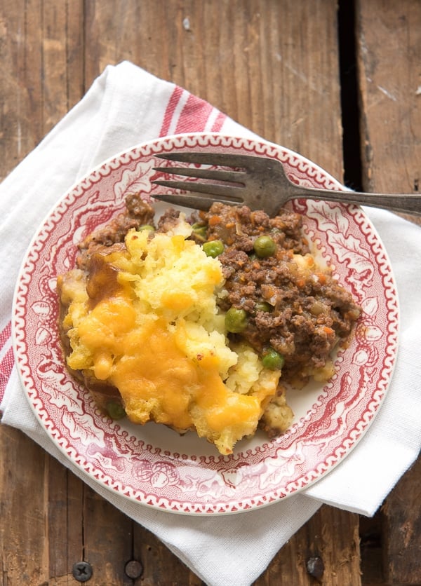 Single serving of Savory Traditional Cottage Pie showing ground meat, peas with cheesy mashed potatoes
