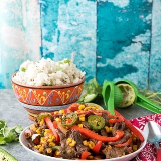 Batch of Spicy Southwestern Steak Stir Fry in a white bowl with Cilantro-Lime Rice and lime juicer