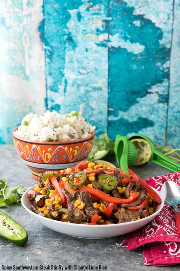 Batch of Spicy Southwestern Steak Stir Fry in a white bowl with Cilantro-Lime Rice and lime juicer