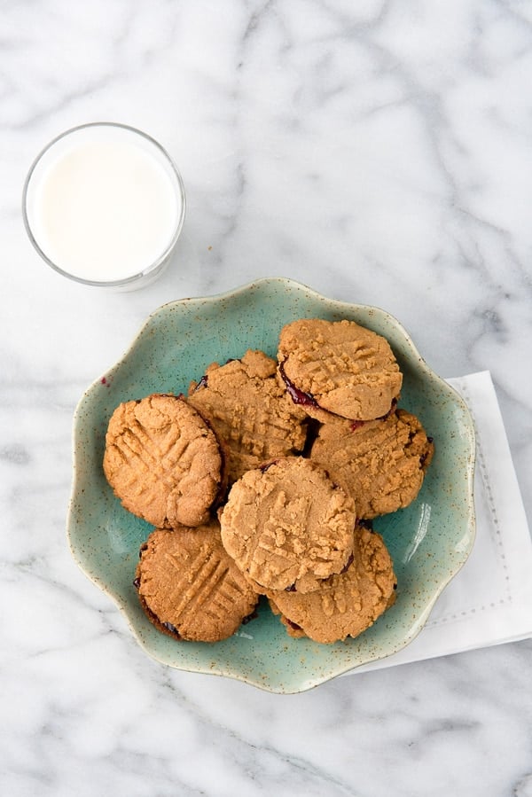 Peanut Butter and Jelly Sandwich Cookies on a blue plate with milk