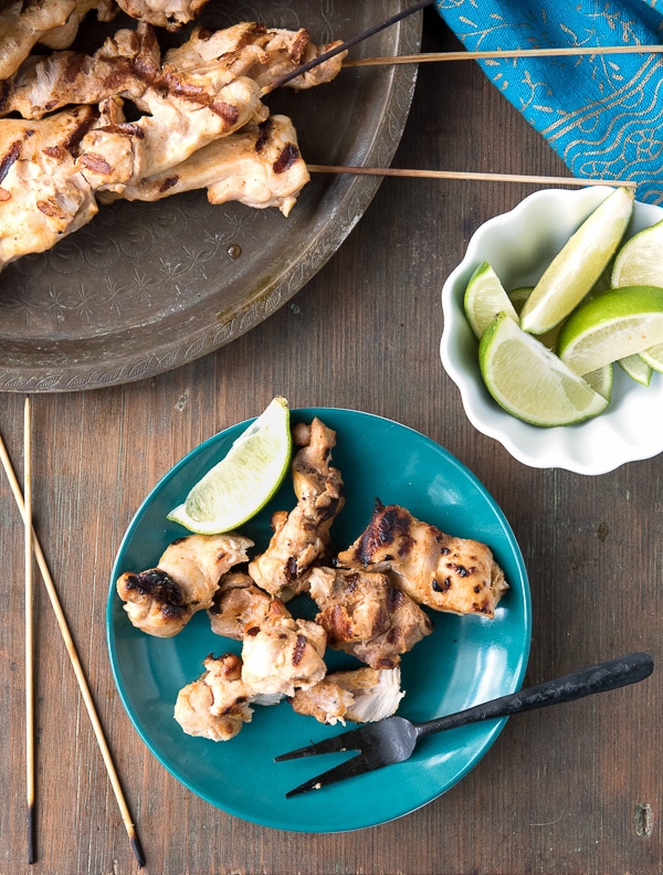 Grilled Chicken Thigh Satay with Peanut Dipping Sauce on blue plate