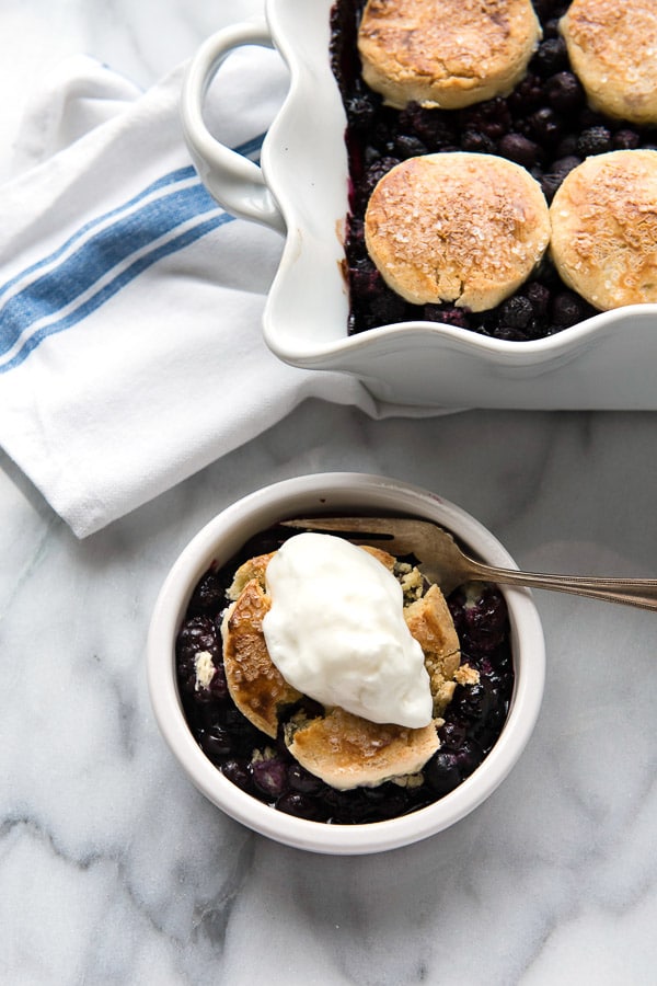 A single serving of Three Berry Cobbler with Sour Cream Biscuits with a dollop of freshly whipped cream