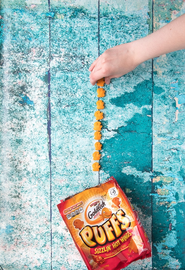 Child\'s Hand picking up gluten-free Goldfish Puffs 