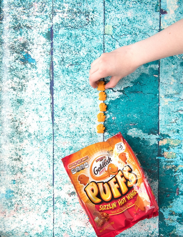 Child\'s Hand picking up gluten-free Goldfish Puffs 