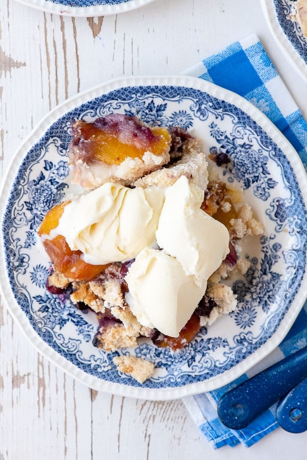 A piece of cake and ice cream on a plate, with Cobbler and Peach