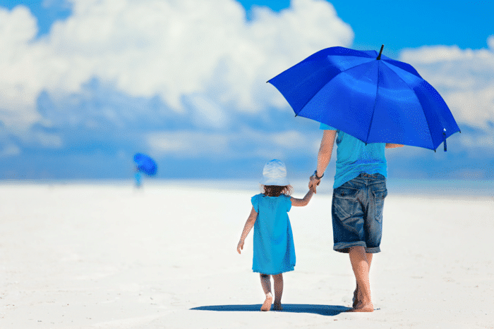 A woman standing on a beach holding a blue umbrella