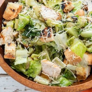 Wooden bowl of Grilled Chicken Caesar Salad with light creamy dressing