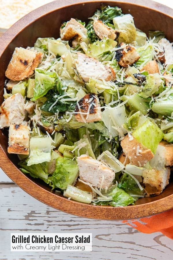 Wooden bowl of Grilled Chicken Caesar Salad with light creamy dressing