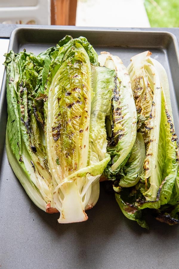 Grilled heads of romaine lettuce on a sheet pan