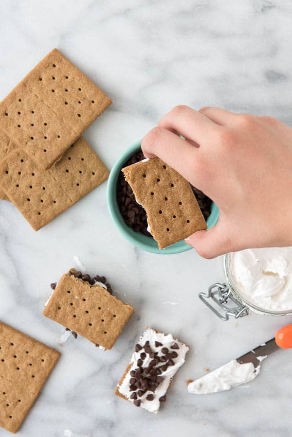 dipping marshmallow fluff on graham cracker into mini chocolate chips