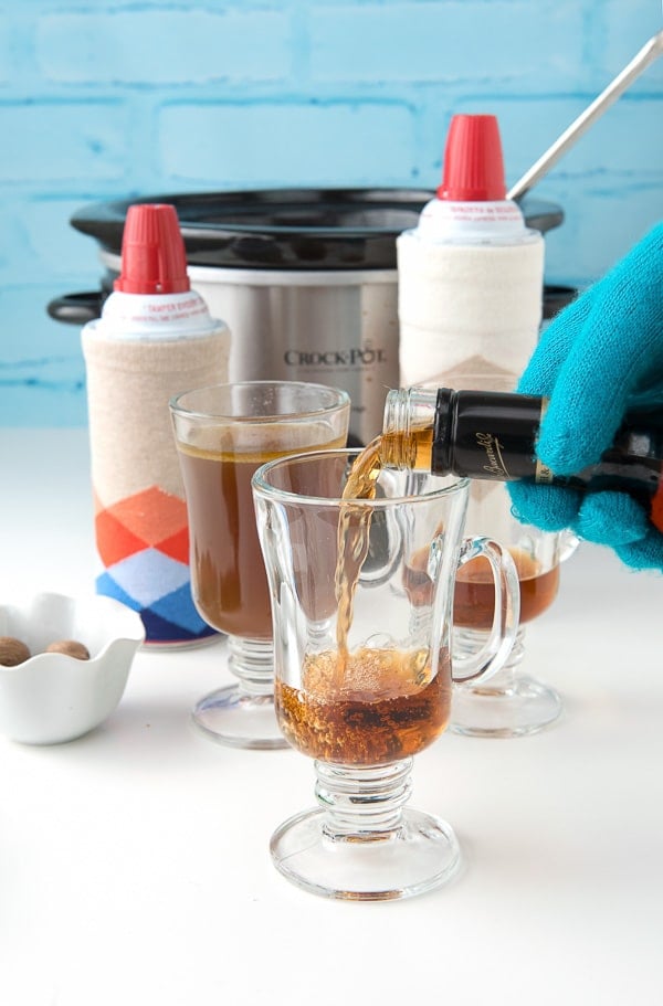 pouring rum into glass mug for Hot Buttered Rum