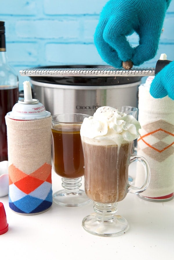 grating whole nutmeg on mug of Hot Buttered Rum