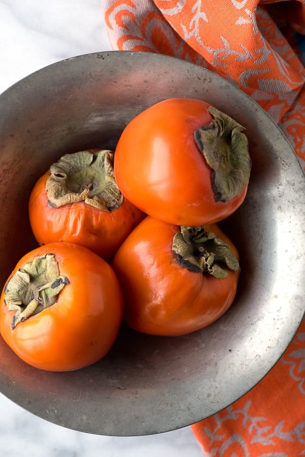 Ripe Hachiya Persimmons in vintage silver bowl 