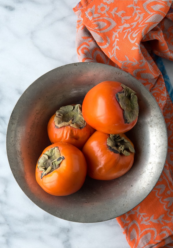 Ripe Hachiya Persimmons in vintage silver bowl 