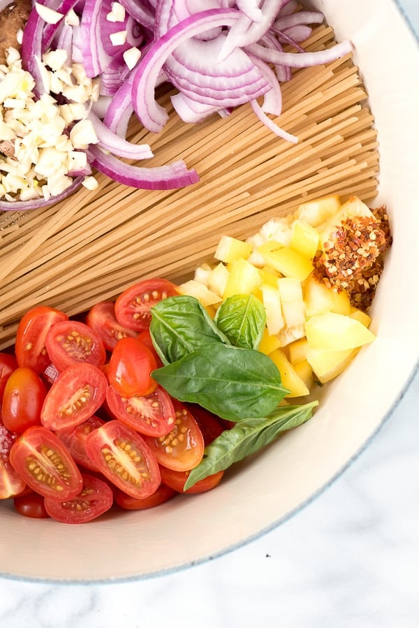 colorful tomatoes, basil, herbs and pasta in dutch oven