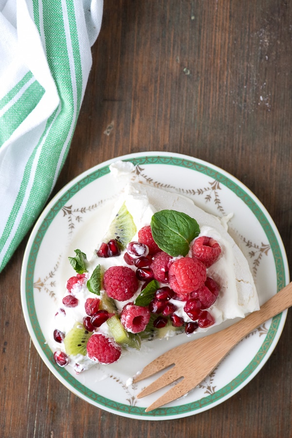 Pavlova with Kiwi, Raspberry, Pomegranate and Mint slice on a plare